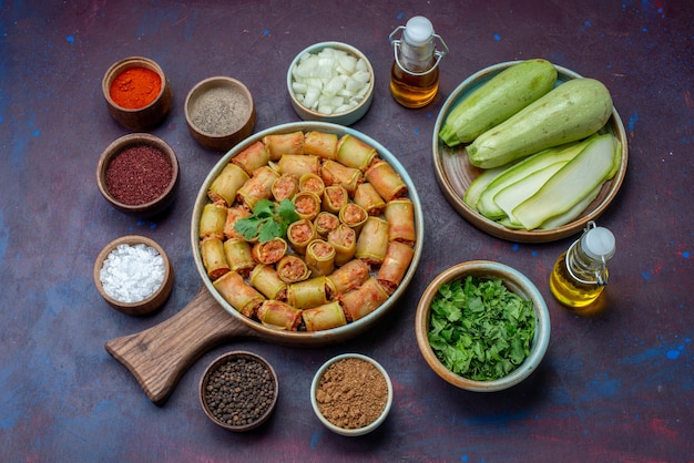 Free photo top view seasonings inside pots salt pepper with fresh squashes meat rolls on the dark-purple surface