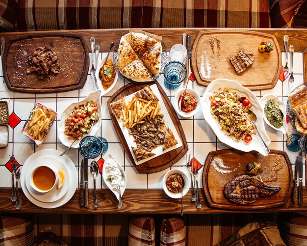 Top view served table with multiple meals and snacks