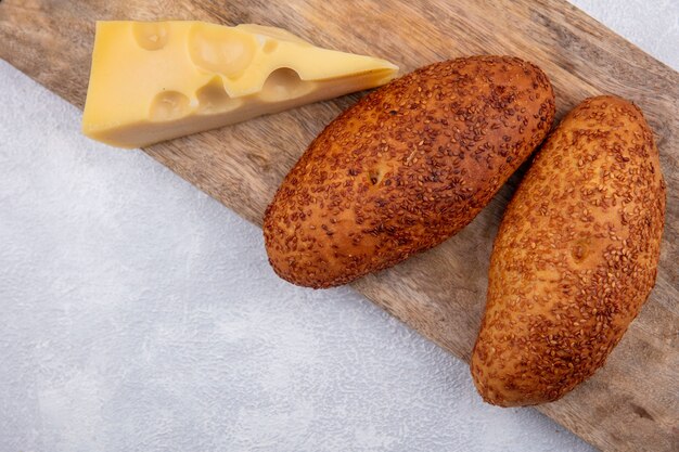 Top view of sesame patties on a wooden kitchen board with cheese on a white background