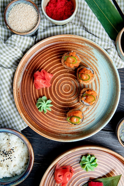 Free photo top view of set of baked sushi rolls with wasabi and ginger on a plate