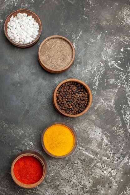 Free Photo top view of set of different spices in brown bowls on gray background