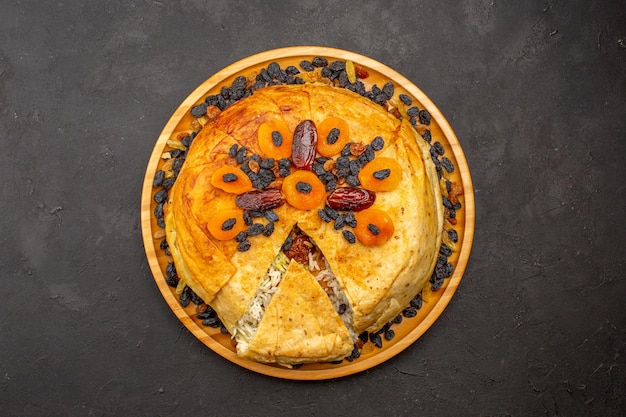 Top view of shakh plov delicious rice meal cooked inside round dough with raisins on dark grey surface