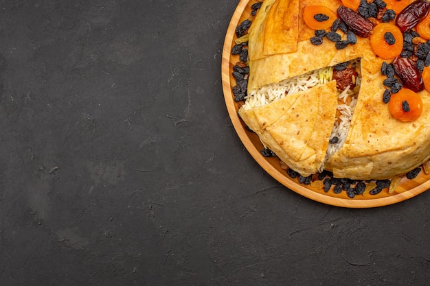 Top view of shakh plov delicious rice meal cooked inside round dough with raisins on a grey surface