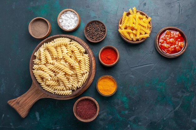 Free photo top view shaped italian pasta with seasonings on the dark-blue desk