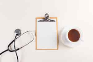 Free photo top view shot of a notepad, medical stethoscope and a cup of a hot tea