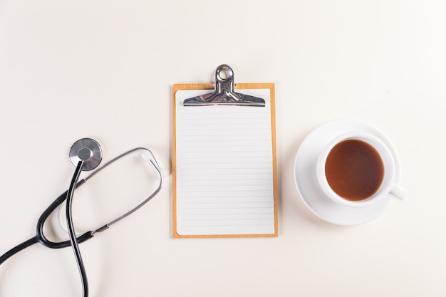 Free Photo top view shot of a notepad, medical stethoscope and a cup of a hot tea