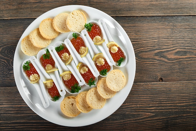 Top view shot of a plate with red caviar servings and crispy rusks on the wooden table food nutrition eating decoration restaurant cafe cafeteria menu order luxury lifestyle concept.