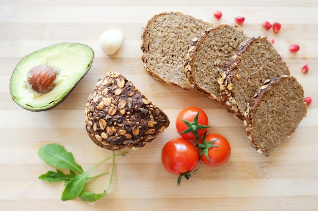 Top view shot of some avocados tomatoes and bread on a cutting board