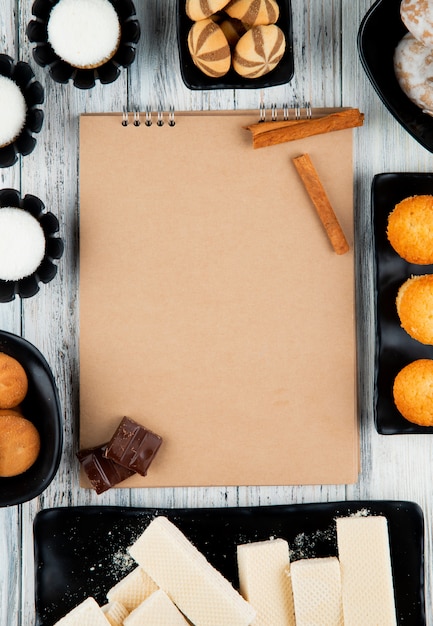 Top view of sketchbook and various types of sweet cookies on wooden rustic background