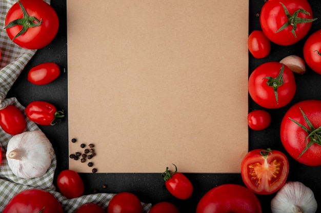 Top view of sketchbook with ripe red tomatoes laying around on black background