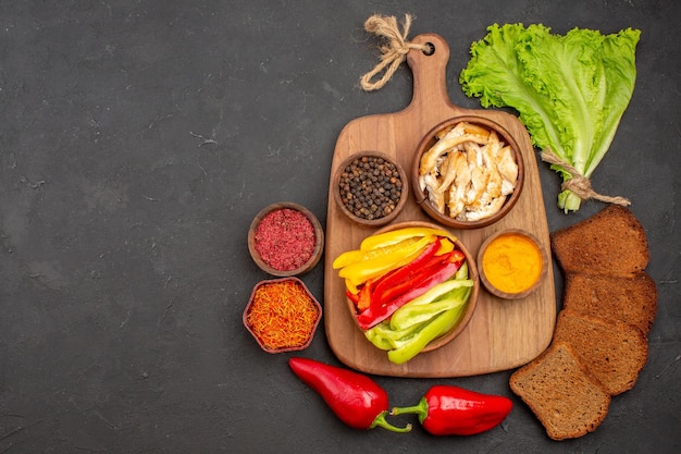 Top view of sliced bell-peppers with seasonings and dark bread on black