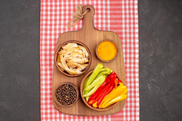 Top view of sliced bell-peppers with seasonings and sliced bread on black