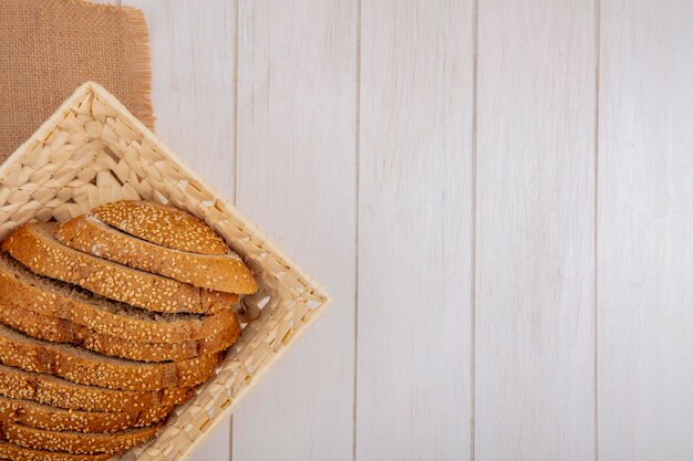 Top view of sliced brown seeded cob in basket on sackcloth on wooden background with copy space