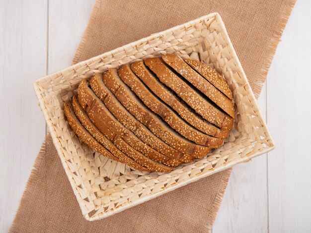 Top view of sliced brown seeded cob in basket on sackcloth on wooden background