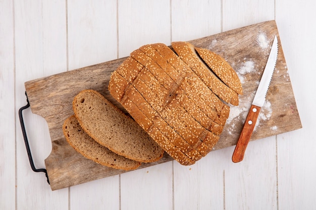 Free Photo top view of sliced brown seeded cob and knife on cutting board on wooden background