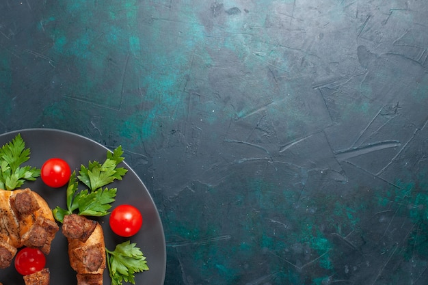 Free photo top view sliced cooked meat with greens cherry tomatoes inside plate on dark-blue background