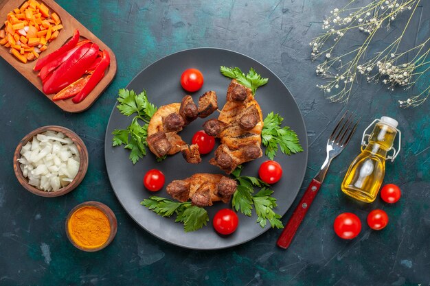 Top view sliced cooked meat with greens cherry tomatoes oil and seasonings on blue background