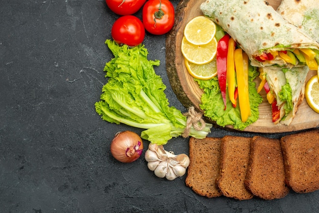 Top view of sliced delicious shaurma meat sandwich with bread and vegetables on black grey