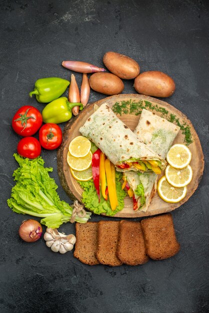 Top view of sliced delicious shaurma meat sandwich with bread and vegetables on black table