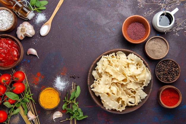 Top view sliced dough with seasonings and tomatoes on the dark background meal dough food pasta dinner