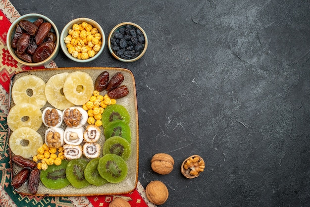 Free Photo top view sliced dried fruits pineapple rings and kiwis on grey background dry fruit raisin sweet vitamine sour health