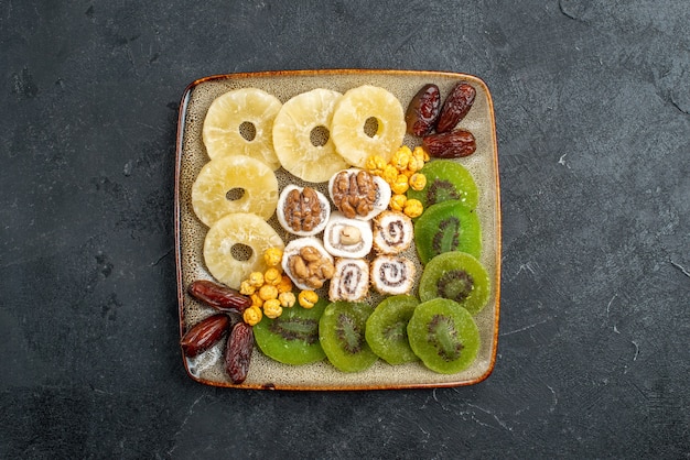 Top view sliced dried fruits pineapple rings and kiwis on grey background dry fruits raisin sweet sour vitamine health