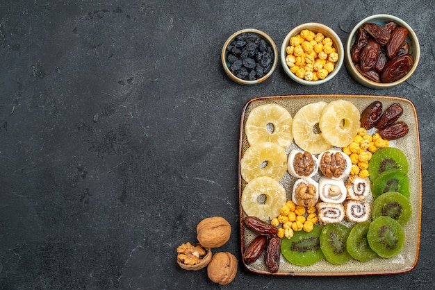 Free Photo top view sliced dried fruits pineapple rings and kiwis on grey background dry fruits raisins sweet vitamine sour health