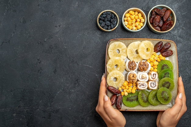 Free photo top view sliced dried fruits pineapple rings and kiwis on a grey desk dry fruit raisin sweet vitamine sour health