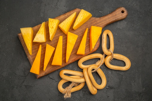 Top view sliced fresh cheese with sweet crackers on dark background