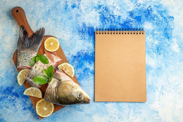 Top view sliced fresh fish with lemon slices on the blue surface