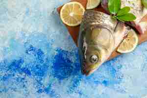 Free photo top view sliced fresh fish with lemon slices on light blue surface