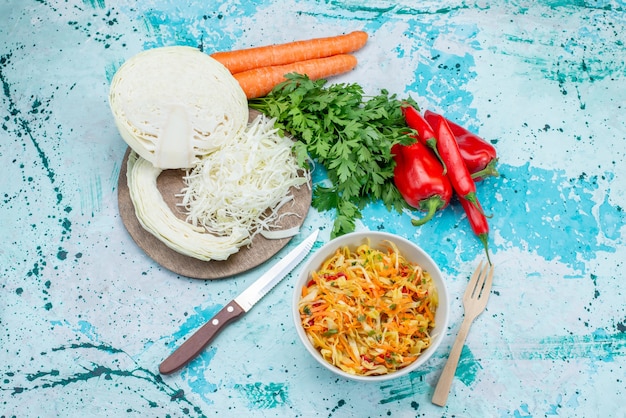 Free photo top view sliced fresh vegetables long and thin pieced salad inside plate with greens cabbage peppers on the bright-blue  surface food meal vegetable lunch healthy salad