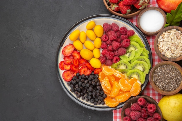 Top view sliced fruits with fresh fruits on a dark background