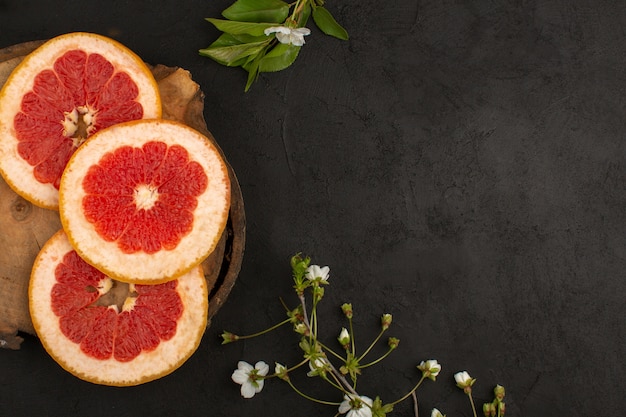 Free photo top view sliced grapefruits rings mellow juicy on the dark background