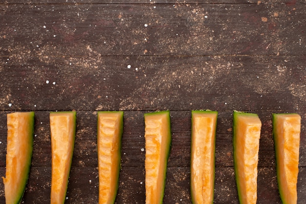 Free photo top view sliced melon green and juicy lined on brown