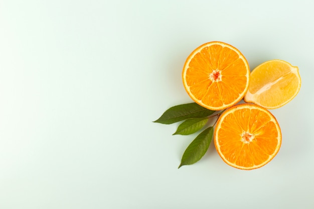 A top view sliced orange fresh ripe juicy mellow isolated half cut pieces with green leaves on the white background fruit color citrus