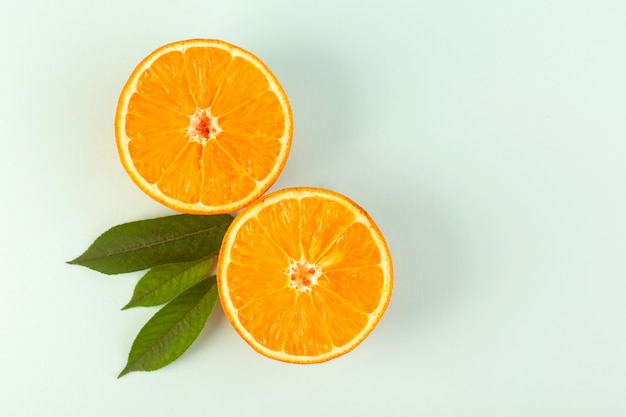 Free photo a top view sliced orange fresh ripe juicy mellow isolated half cut pieces with green leaves on the white background fruit color citrus