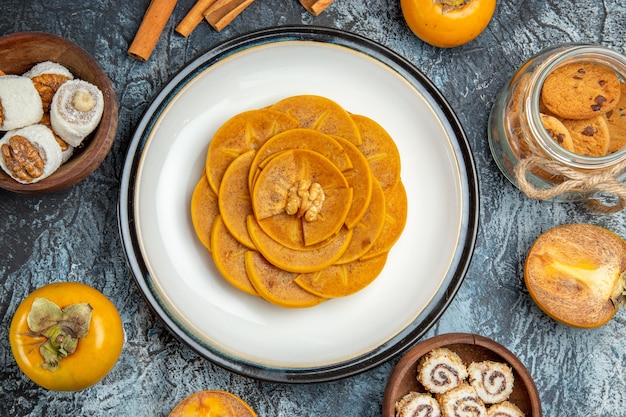 Free photo top view of sliced persimmon on pancake on a light surface