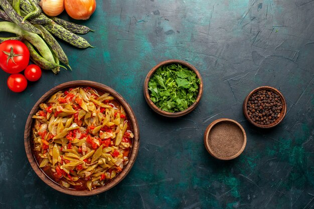 Top view sliced vegetable meal with different ingredients inside plate on dark-blue desk