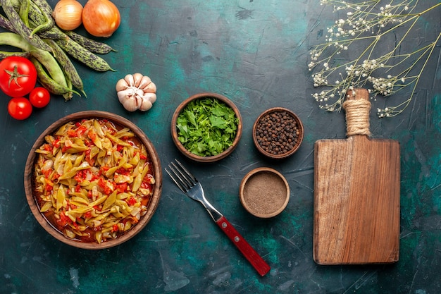 Top view sliced vegetable meal with different ingredients and seasonings on dark-blue background