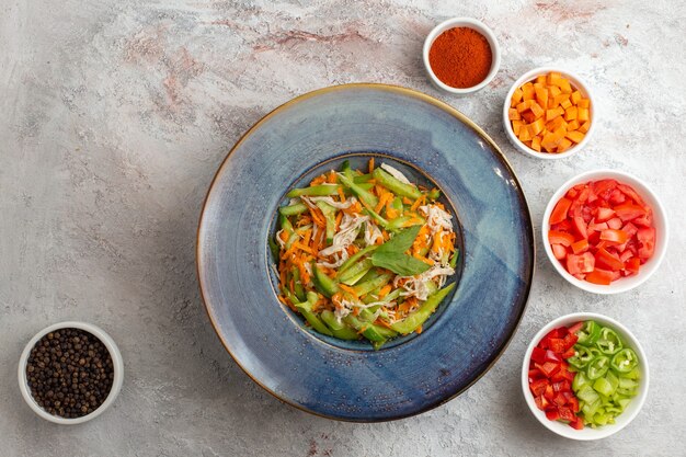 Top view sliced vegetable salad with seasonings and other sliced vegetables on the white background