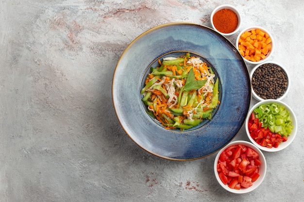 Top view sliced vegetable salad with seasonings on white background