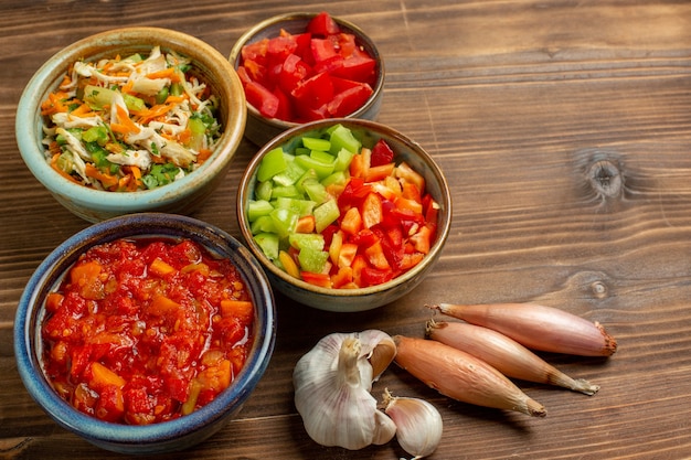 Free photo top view sliced vegetables bell-peppers with tomato on a brown wooden background vegetable meal food salad health