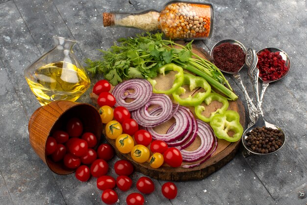 top view sliced whole vegetables such as onions green bell peppers tomatoes on the brown wooden desk and grey floor