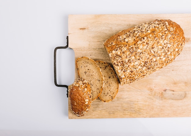 Top view of sliced wholegrain bread on chopping board over white background