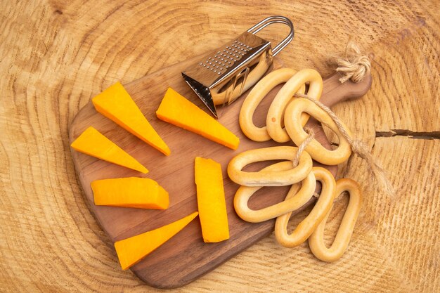 Top view slices of cheese box grater oval bagels on cutting board on wooden ground