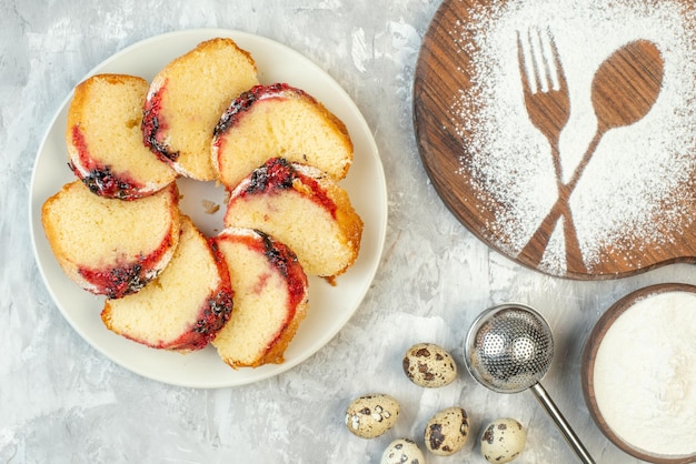 Free photo top view slices of jam cake on plate quail eggs fork and spoon imprinted on wood board with flour