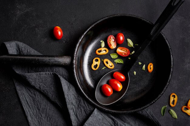 Top view slices of tomatoes and chilli pepper in frying pan