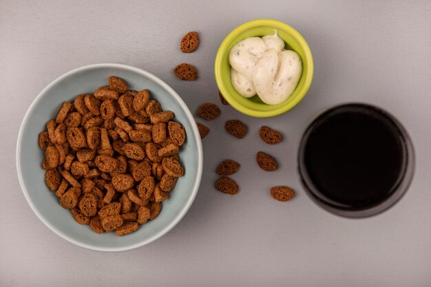 Top view of small rye rusks on a bowl with a glass of cola with sauce