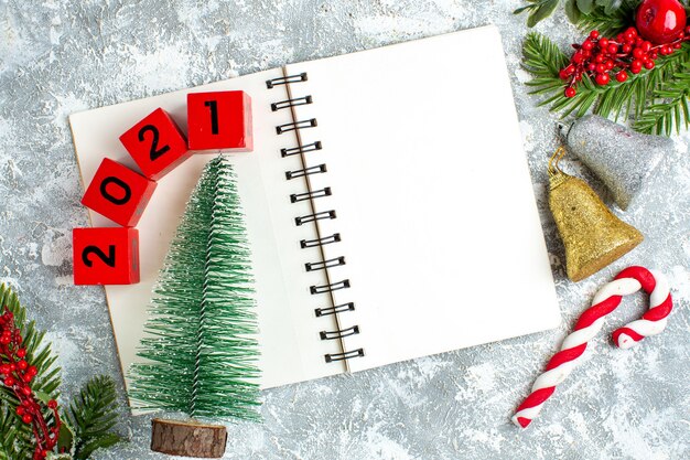 Top view small xmas tree wood blocks on notepad xmas bells on grey white table